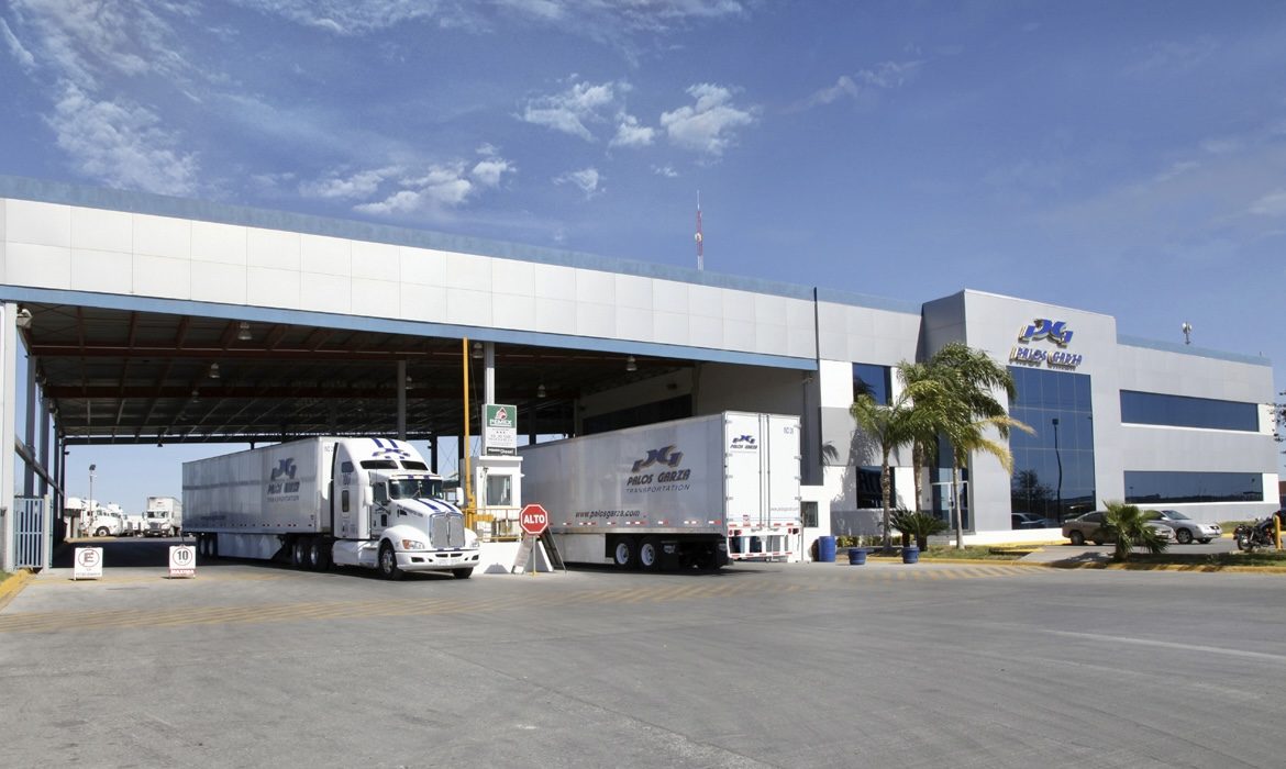 Palos Garza cross-dock terminal with company trucks staged under the loading canopy.